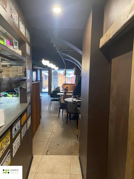 Interior of a dining area with plates on a shelf, blackboards, tables, and chairs.