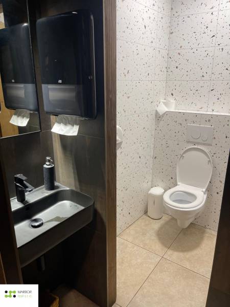Restroom in dining spaces with a sink, mirror, and terrazzo tiles.