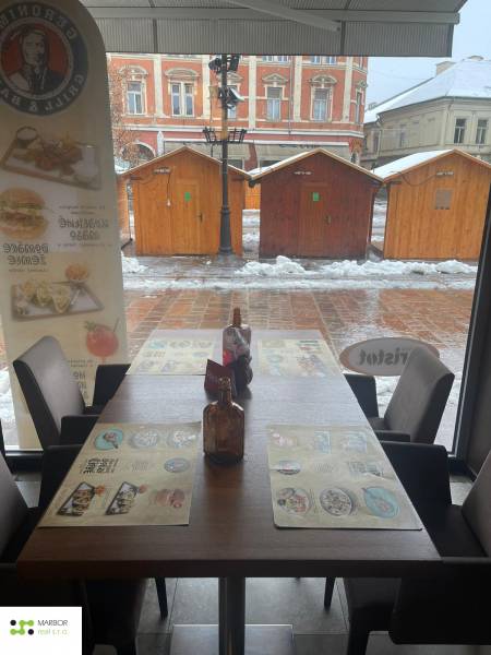 Winter scenery through the window of a gastro space with a view of wooden tables.