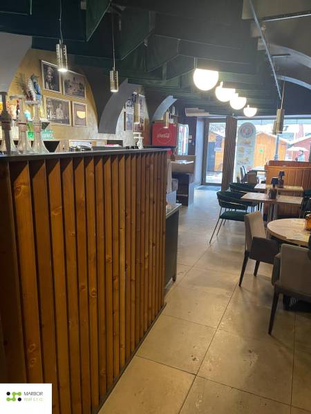 Interior of a gastro space with a wooden bar and tables. Decorative lighting is also visible.