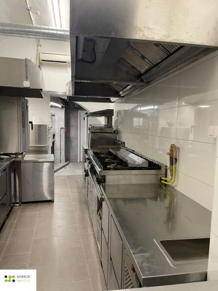 Professional kitchen with stainless steel appliances and white tiles in the gastro area.