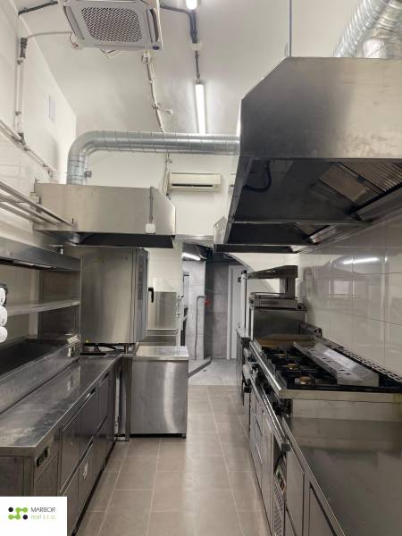 Professional kitchen with metal equipment and wood-decor flooring in gastro premises.