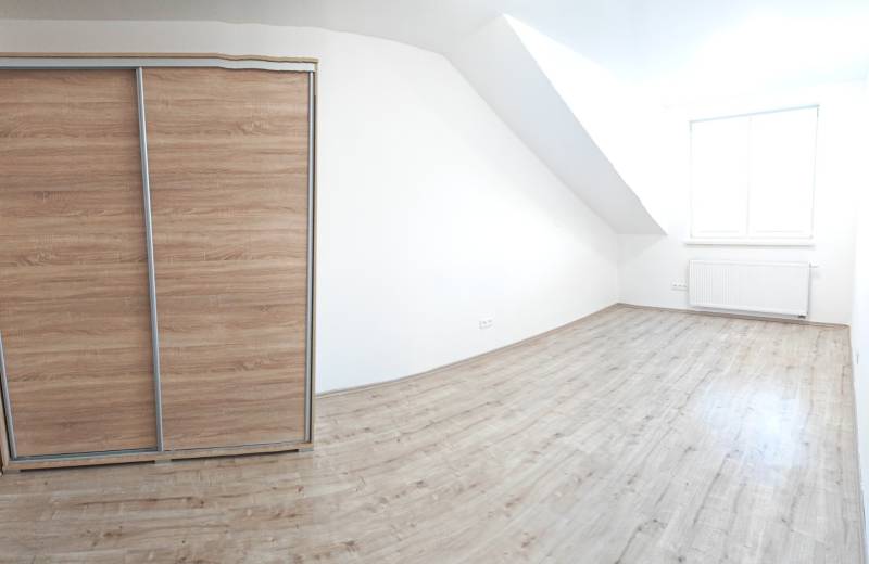 A bright room with white walls and a wardrobe, floor with wooden decor.