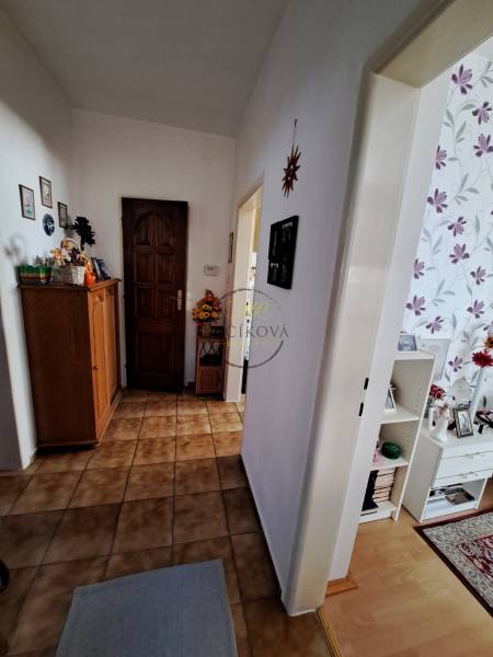 Hallway in a family house with tiled flooring and floral wallpaper decoration on the wall.