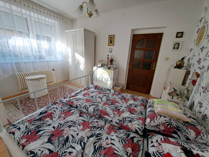 Bedroom in a family house with a bed, wardrobe, and decorative carpet.