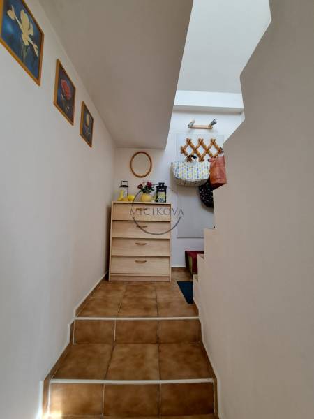 Hallway of a family house with stairs, wooden furniture, decorations, and wall hooks.