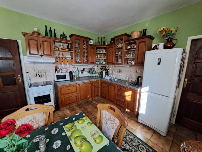 A kitchen in a family house with wooden furniture and decorations on the shelves.