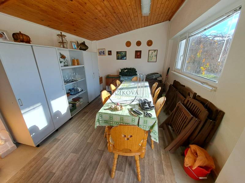 Interior of a family house with a wooden decor floor, dining table, and display cabinet.