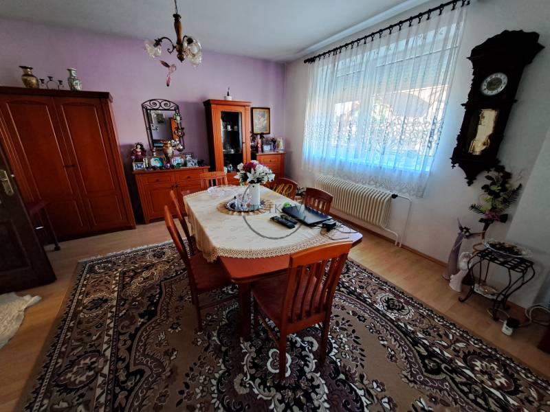 Dining room with solid wood furniture, clock on the wall, floor with wooden decor, family house.