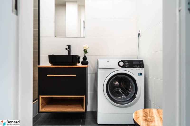 A bathroom in a 2-room apartment with a sink, washing machine, and black accessories.