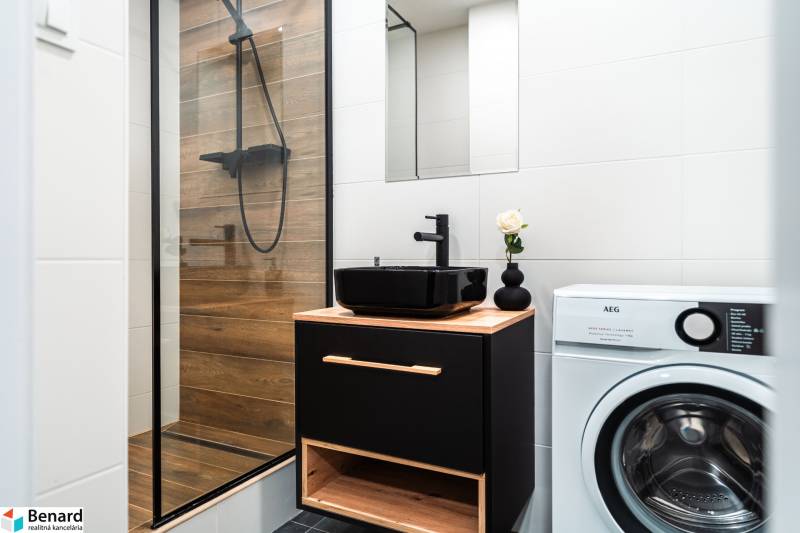 Bathroom in a 2-room apartment with wooden decor, black sink, and washing machine.