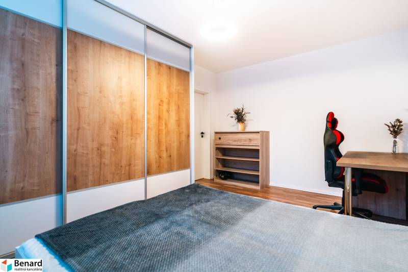 A room in a 2-room apartment with a wooden decor floor, a wardrobe, and a desk.