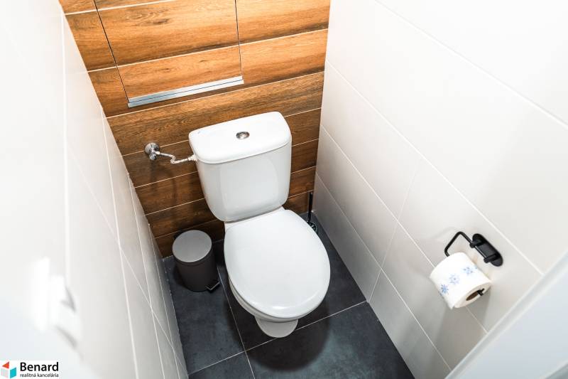 A toilet in a 2-room apartment with wooden decor and white tiles.