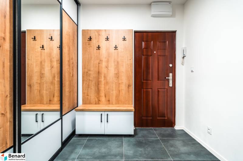 A hallway in a 2-room apartment with wooden decor, a mirror, and tiles.
