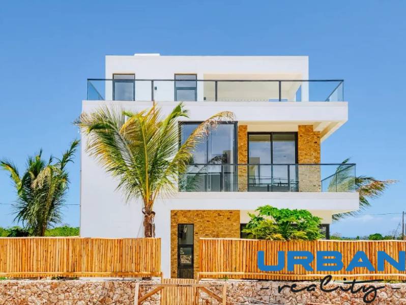 A villa in Fumba Town with glass balconies and exotic palm trees in the foreground.