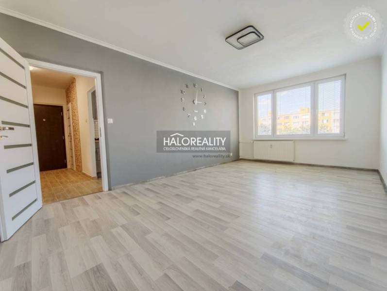 Living room in a two-room apartment with a wooden decor floor and large windows.