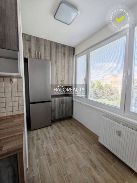 A kitchen in a 2-room apartment with a light wood-patterned floor and large windows.