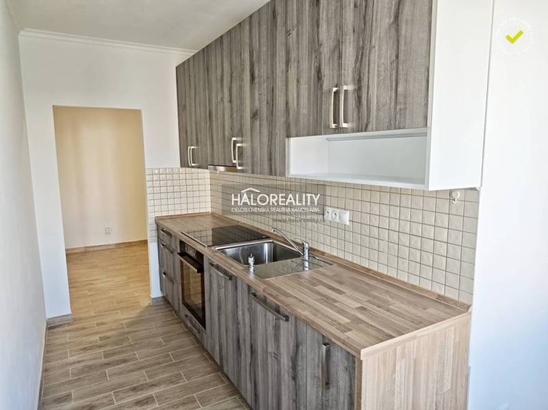 A kitchen in a 2-room apartment with a wooden decor floor and tiles on the wall.