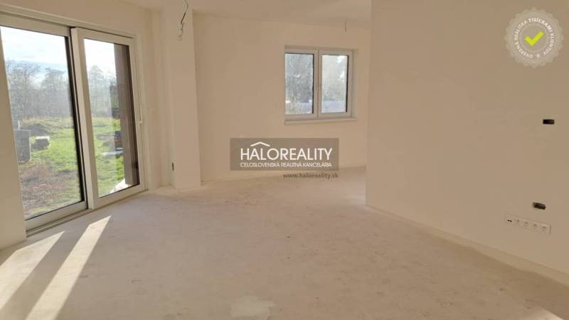Interior of a family house with a large window, white walls, and patio doors.
