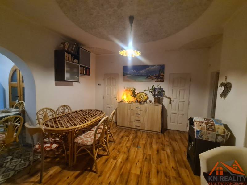 Interior of a family house with a wooden decor floor, a large table, and decorations.