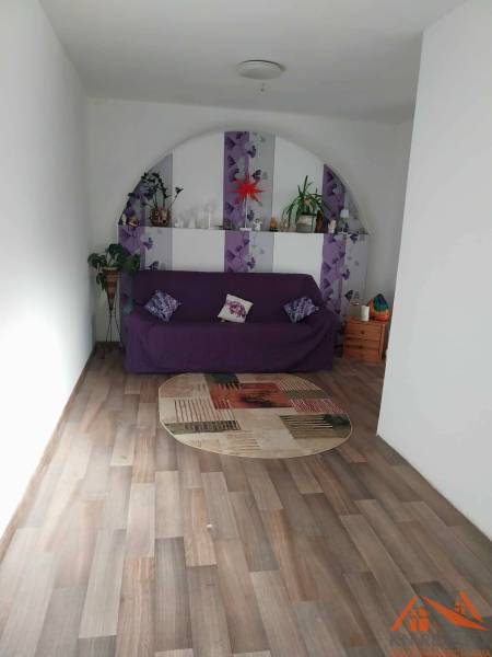 Living room in a family house with a purple sofa and a wood-patterned floor.