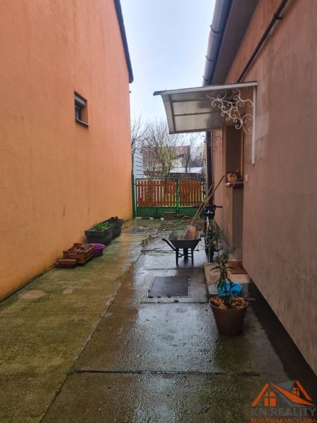 The courtyard of a family house in Komárno with numerous flower pots and storage space.