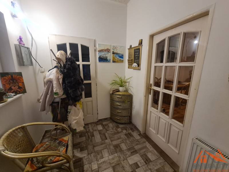 A hallway of a family house with a chair, wall pictures, and a coat rack.