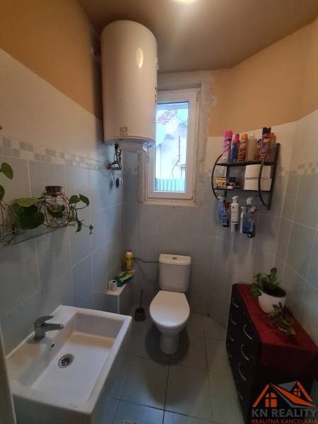 A bathroom in a family house with sanitary facilities, a water heater, and a window.