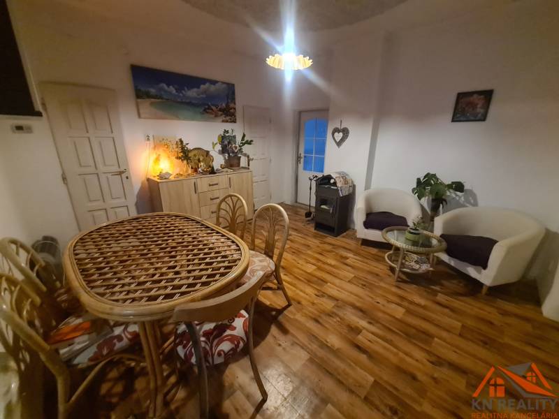 Interior of a family house with a wooden decor floor, a wicker table, and comfortable armchairs.