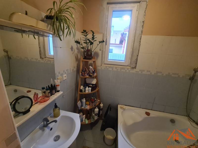 Bathroom in a family house with a bathtub, mirror, and shelf for toiletries.