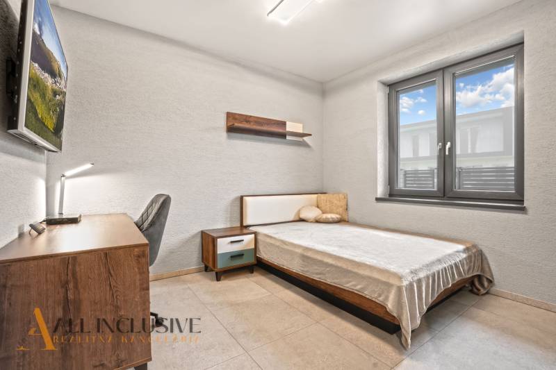 A bedroom in a family house with simple furnishings, a desk, and a comfortable bed.