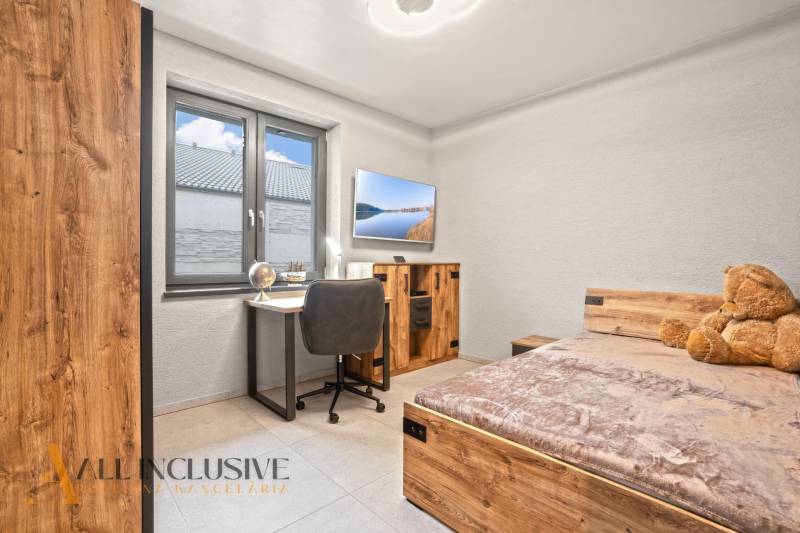 Children's room in a family house with a desk, bed, and wooden decor flooring.