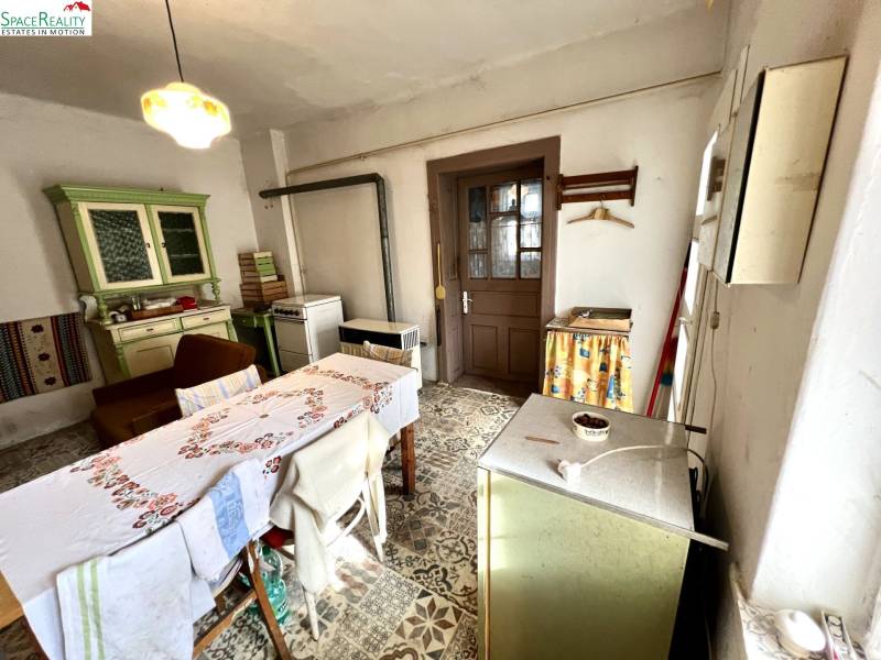 Dining room in a family house with a stove, table, and old furniture.
