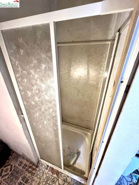 Shower enclosure in the interior of a family house with tiling and decorative flooring.