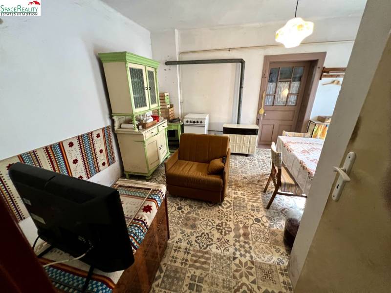 A living room in a family house with rustic furniture and patterned flooring.