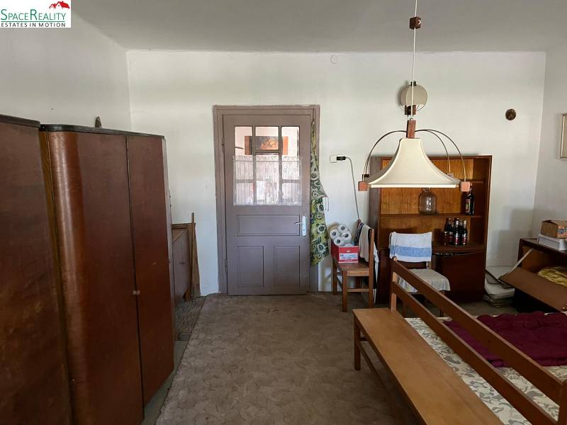 Interior of a family house with furniture and a carpet, a central lamp, and a shelf with drinks.