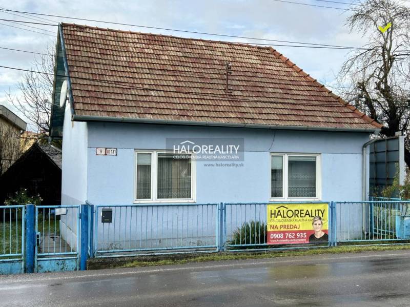 A single-story family house in Prievidza, blue facades, sloped roof, metal fence.