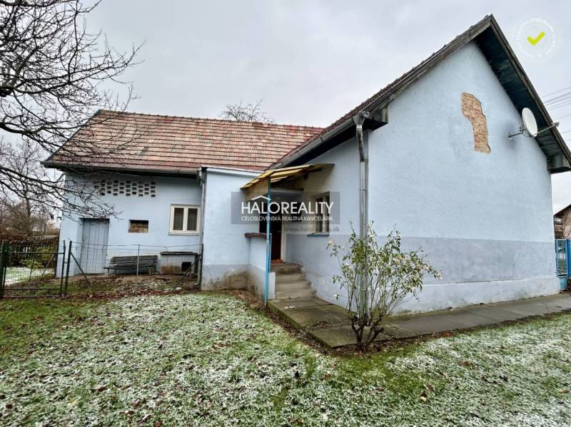 A family house in Prievidza with a blue facade, a yard, and a part of the lawn with frost.