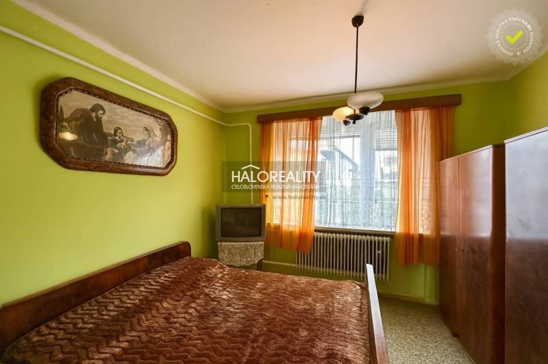 Bedroom in a family house with a bed, painting, cabinet, and television.