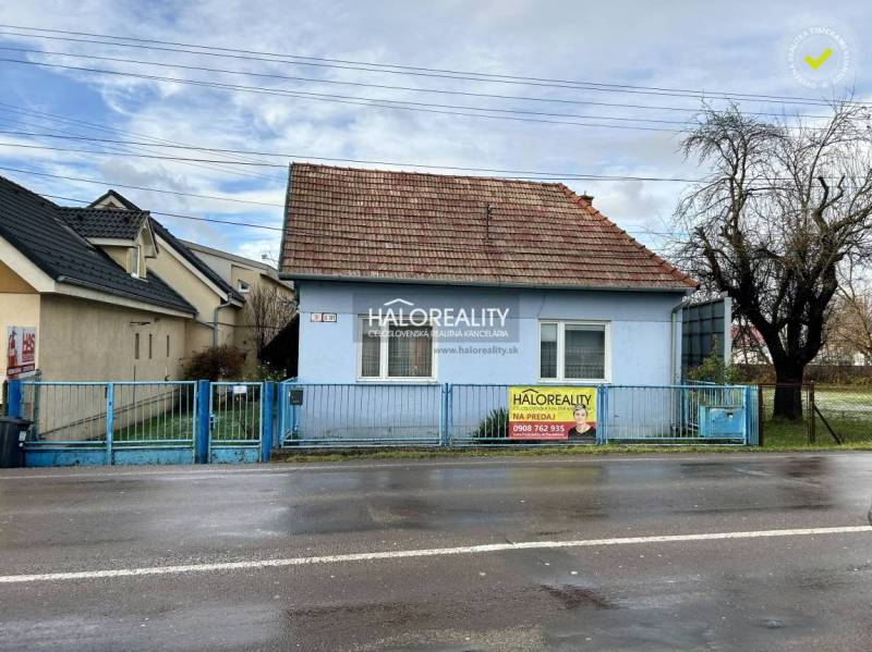 A family house in Prievidza, blue facade, sloped roof, and front fence.