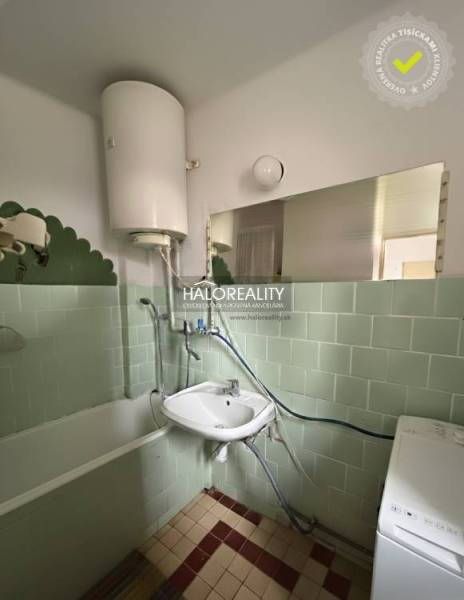 A bathroom in a 3-room apartment with a bathtub, sink, washing machine, and green wall tiles.