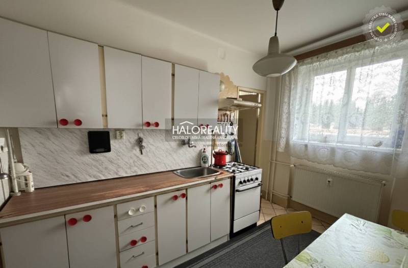 A kitchen in a 3-room apartment with white cabinets and a kitchen counter with a wood decor.