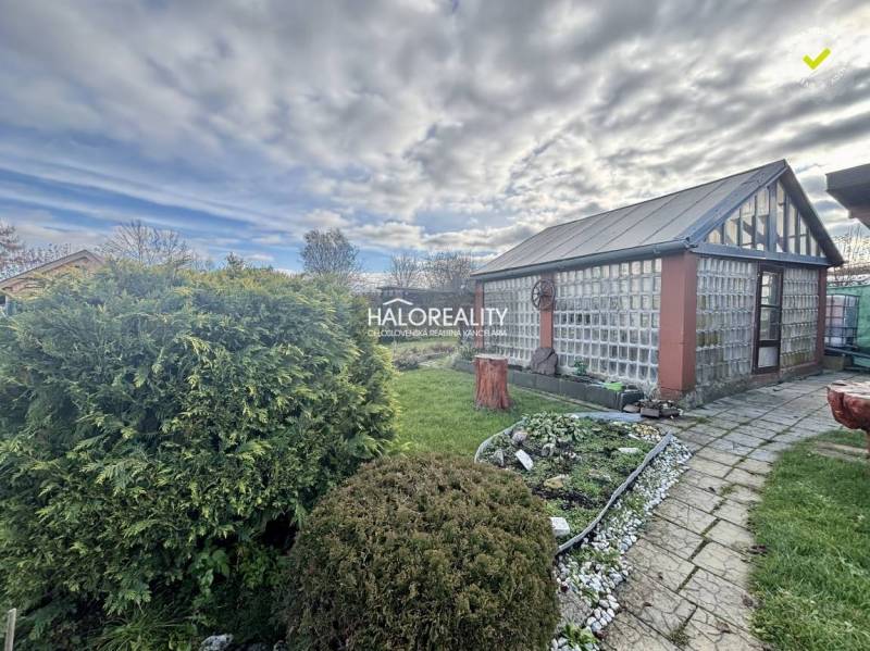 Gardens in Spišská Nová Ves with a glass house, manicured lawn, and flower bed.