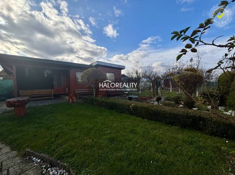 A wooden gazebo in the garden in Spišská Nová Ves with a green lawn and greenery.