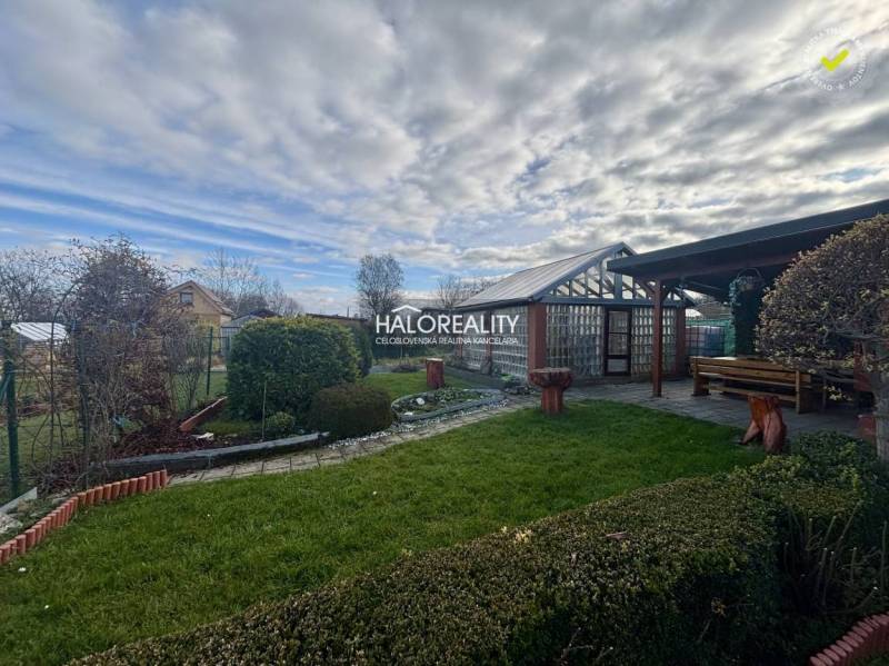 Gardens of Spišská Nová Ves with trimmed bushes, lawn, and wooden shelter.