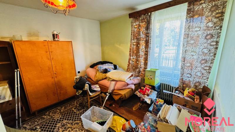 A room in a family house with clutter, old furniture, and a view through the window.
