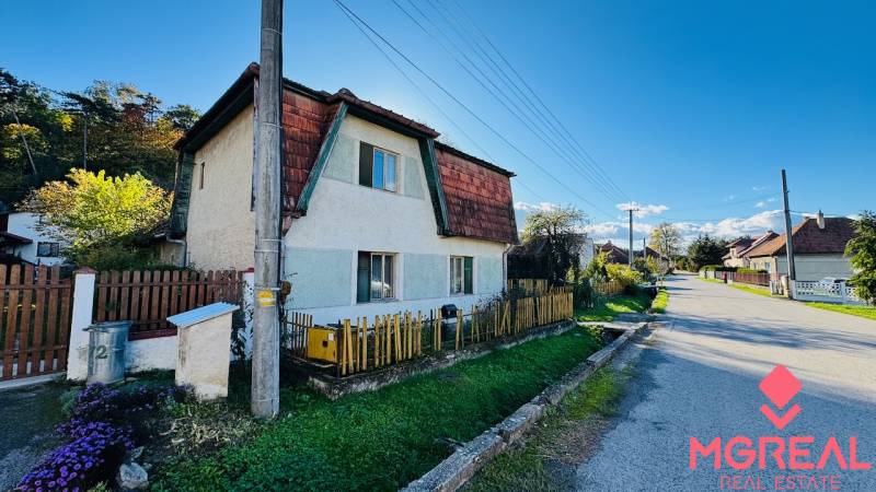 A family house in Brodzany with a wooden fence and a well-maintained garden on a quiet street.