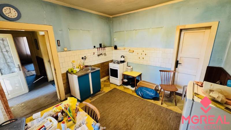 A kitchen in a family house with blue walls, older furniture, and practical equipment.