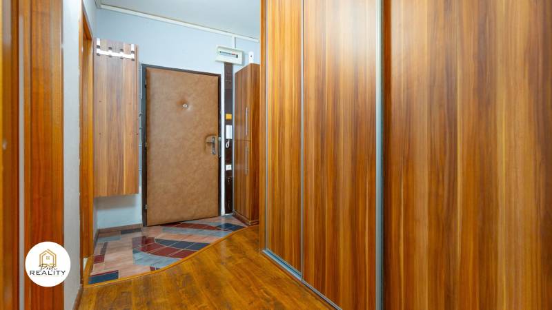 A hallway with wooden decor wardrobes in a 4-room apartment, doors with a security lock.