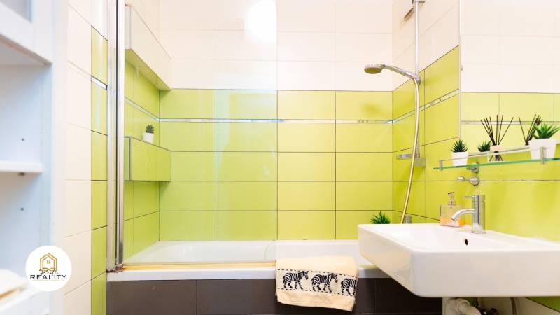 A bathroom in a 4-room apartment with a bathtub, sink, and green tiles.